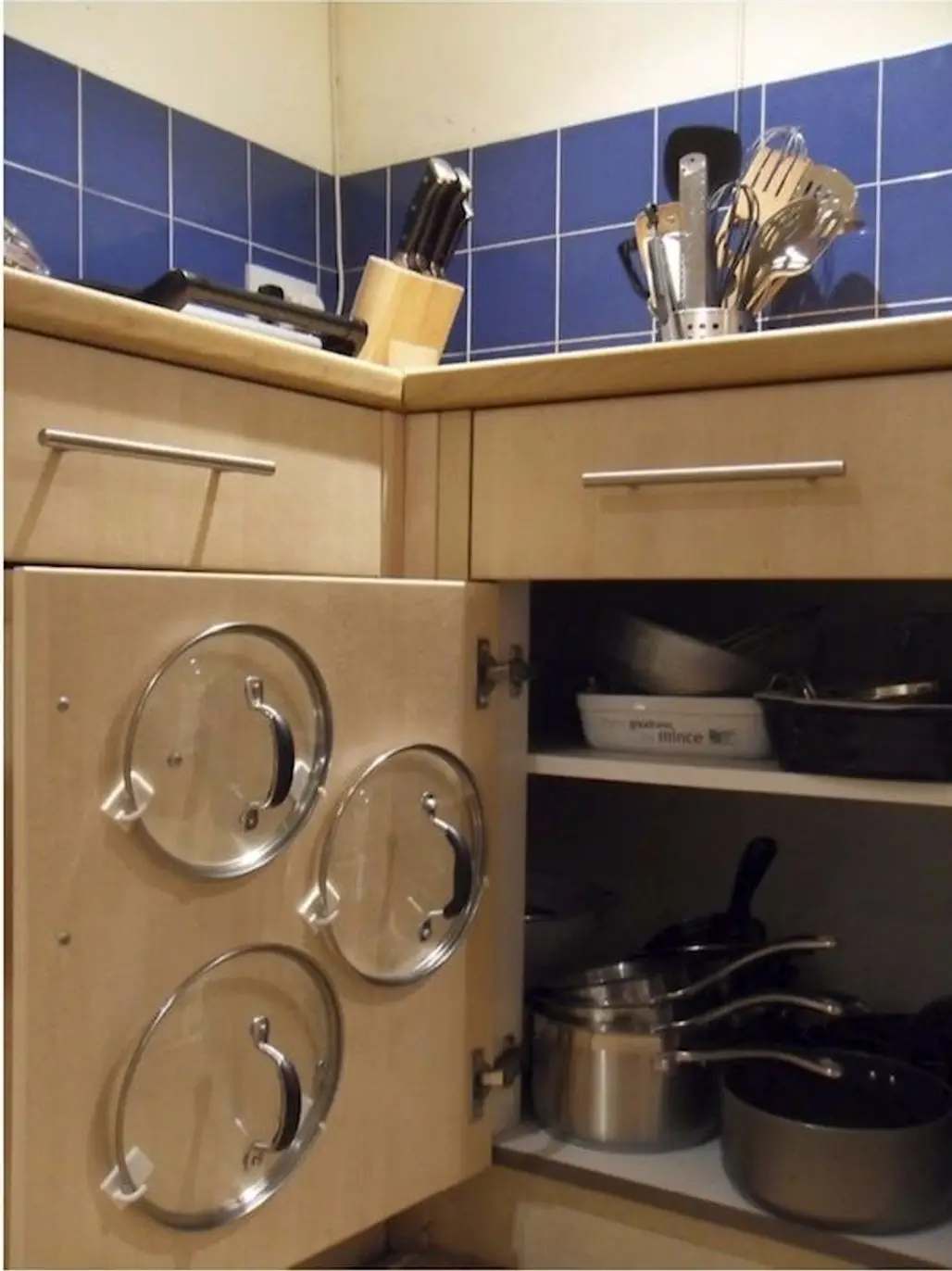 Adhesive Hooks inside a Cupboard Door Will Keep Lids Organized